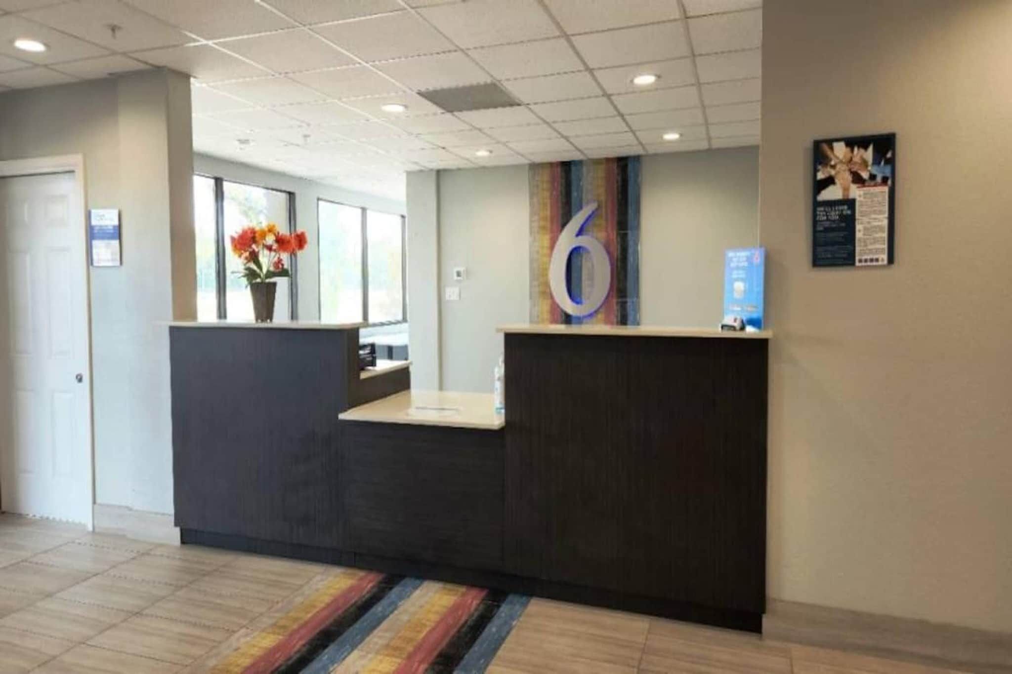 A reception desk with a large number '6' sign, a flower vase, and a poster on the wall.