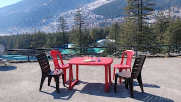 A table and chairs set outdoors with a mountain view in the background.