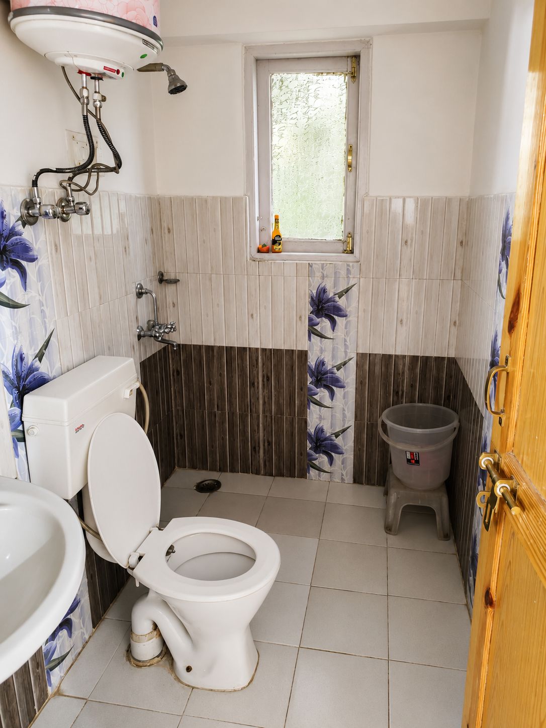 A bathroom with a toilet, a sink, a shower, and a window.