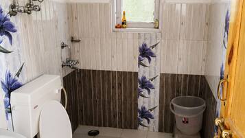 A bathroom with a toilet, a sink, a shower, and a window.
