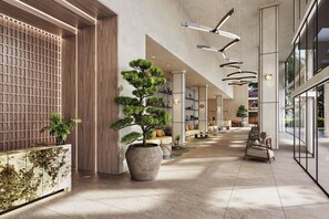 A modern interior with a long corridor, large potted plants, and contemporary furniture. - King Suite | Rooftop Views | Theatre Lawn | Pool | Gym | Nexo Miami by AvantStay (North Miami Beach)
