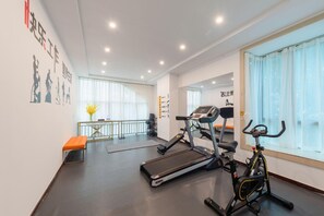 Un gimnasio con cintas de correr, elípticas y una banca.