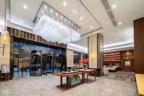 A hotel lobby with a revolving door, a reception desk, and a seating area with a table and chairs. - Echeng Hotel Nanning Baisha Avenue (Nanning)