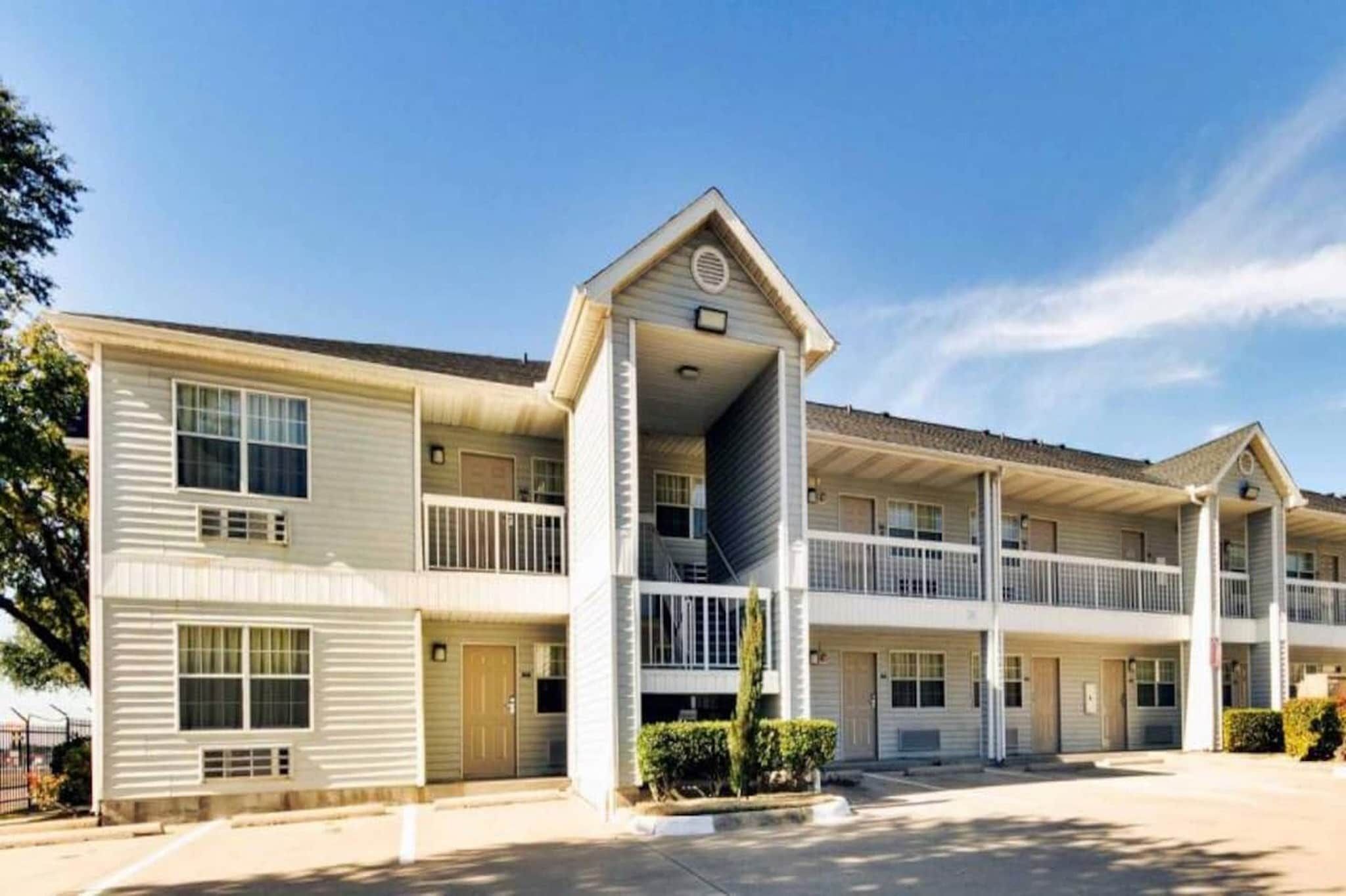 A multi-story motel with a central entrance, balconies, and a parking area.