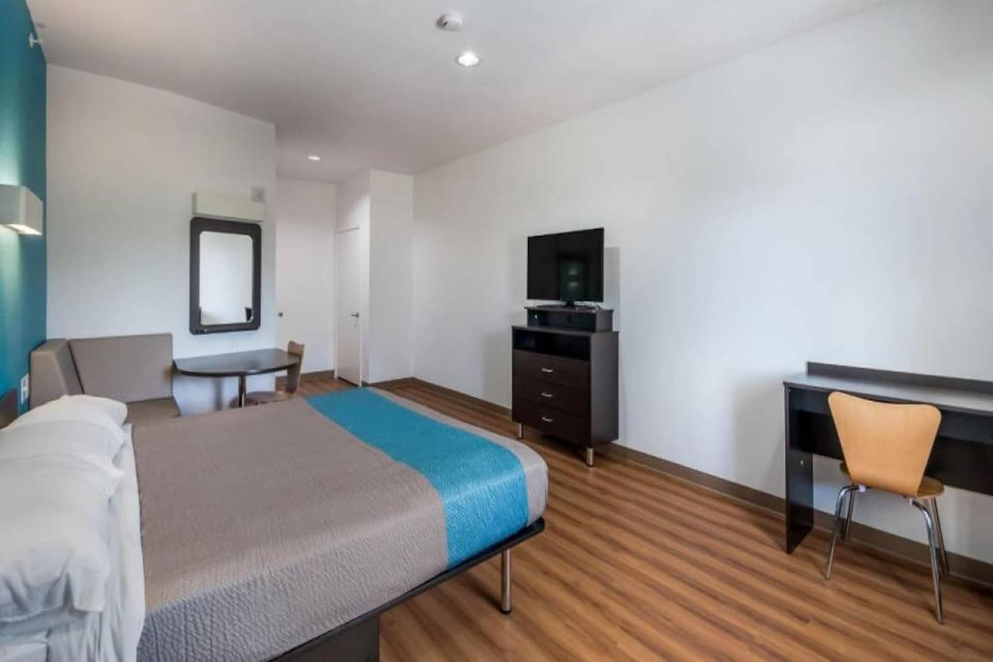 A hotel room with a bed, a desk, a chair, a TV, and a wardrobe.