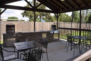 Un patio al aire libre con una parrilla, una mesa y sillas.