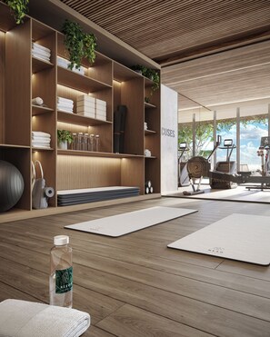 Ein moderner Wellnessraum mit Holzregalen, Yogamatten und Trainingsgeräten.