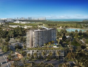 A high-rise hotel with multiple balconies, surrounded by greenery and a view of the ocean. - Signature Suite | Rooftop Views | Fitness Center | Resort Pool | Nexo Miami (North Miami Beach)