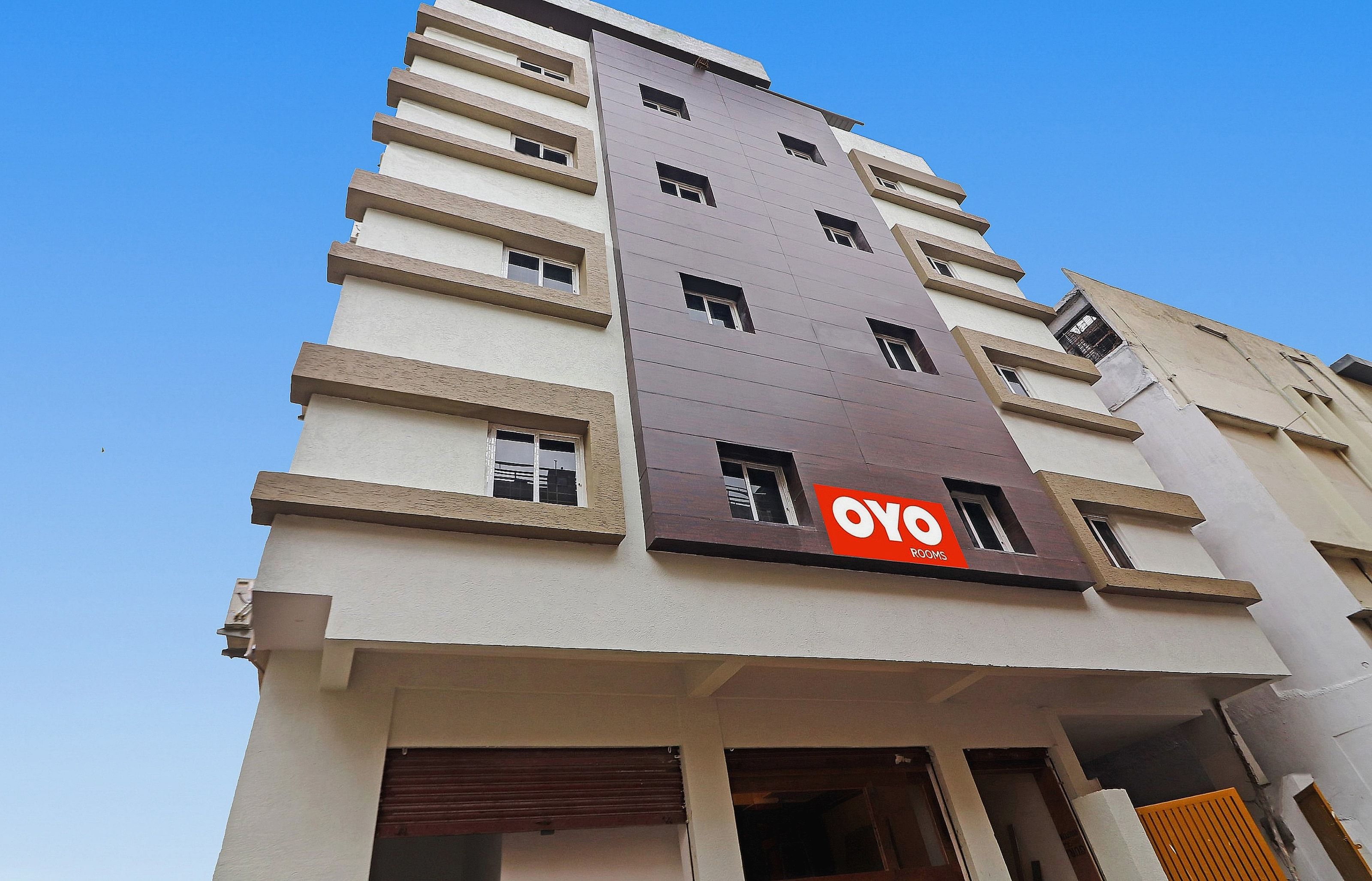 Um edifício de vários andares com uma placa indicando 'OYO Rooms', sinalizando um hotel ou serviço de hospedagem.