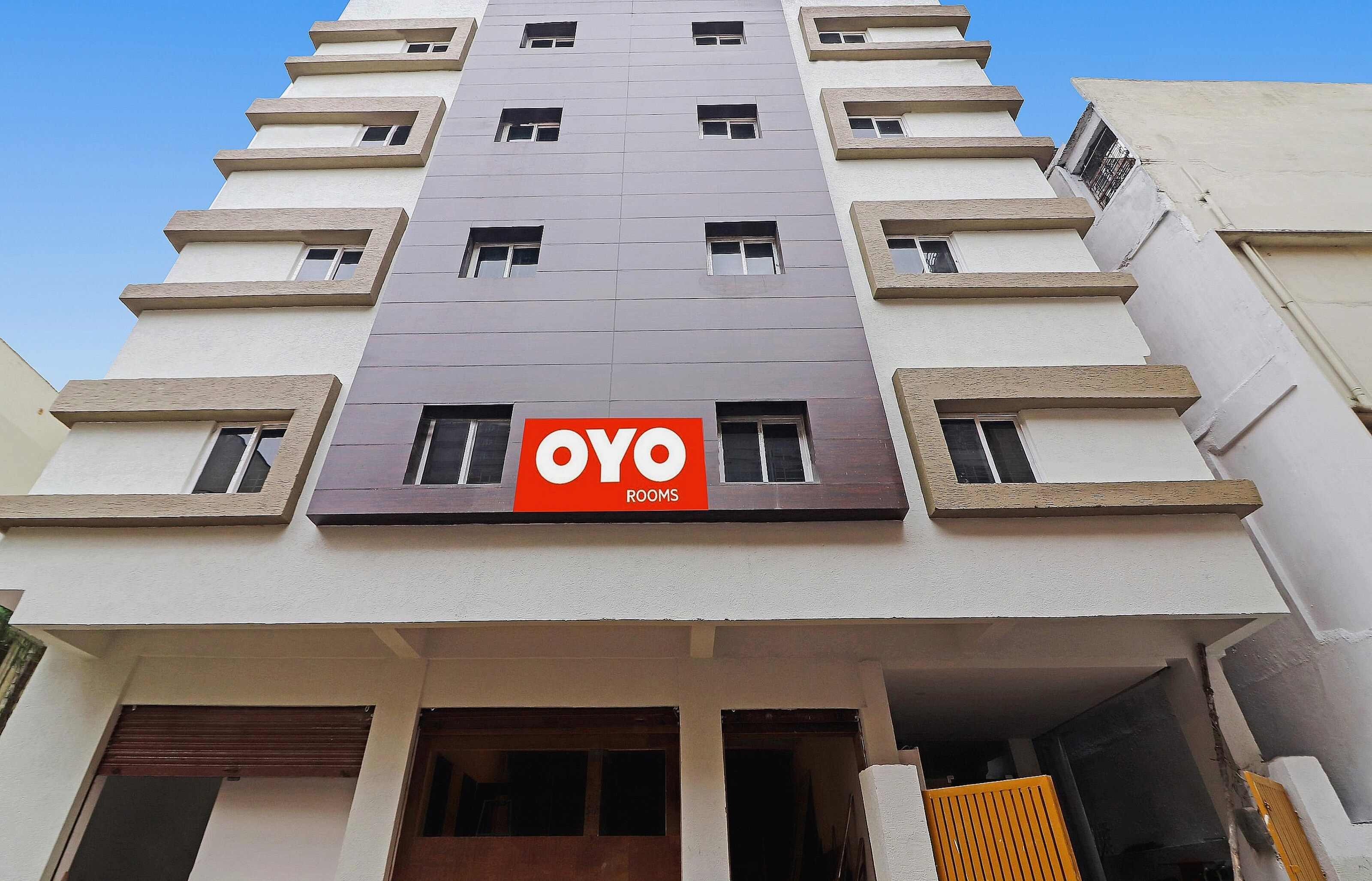 Un edificio de varios pisos con un llamativo letrero que dice 'OYO ROOMS' en la fachada.