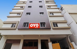 Edifício de vários andares com uma placa grande de 'OYO ROOMS' na fachada.