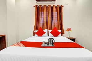 A hotel room with a bed, a nightstand, a vase with flowers, and a tray with a kettle and cups. - Hotel O by OYO Night Eye (Hyderabad)