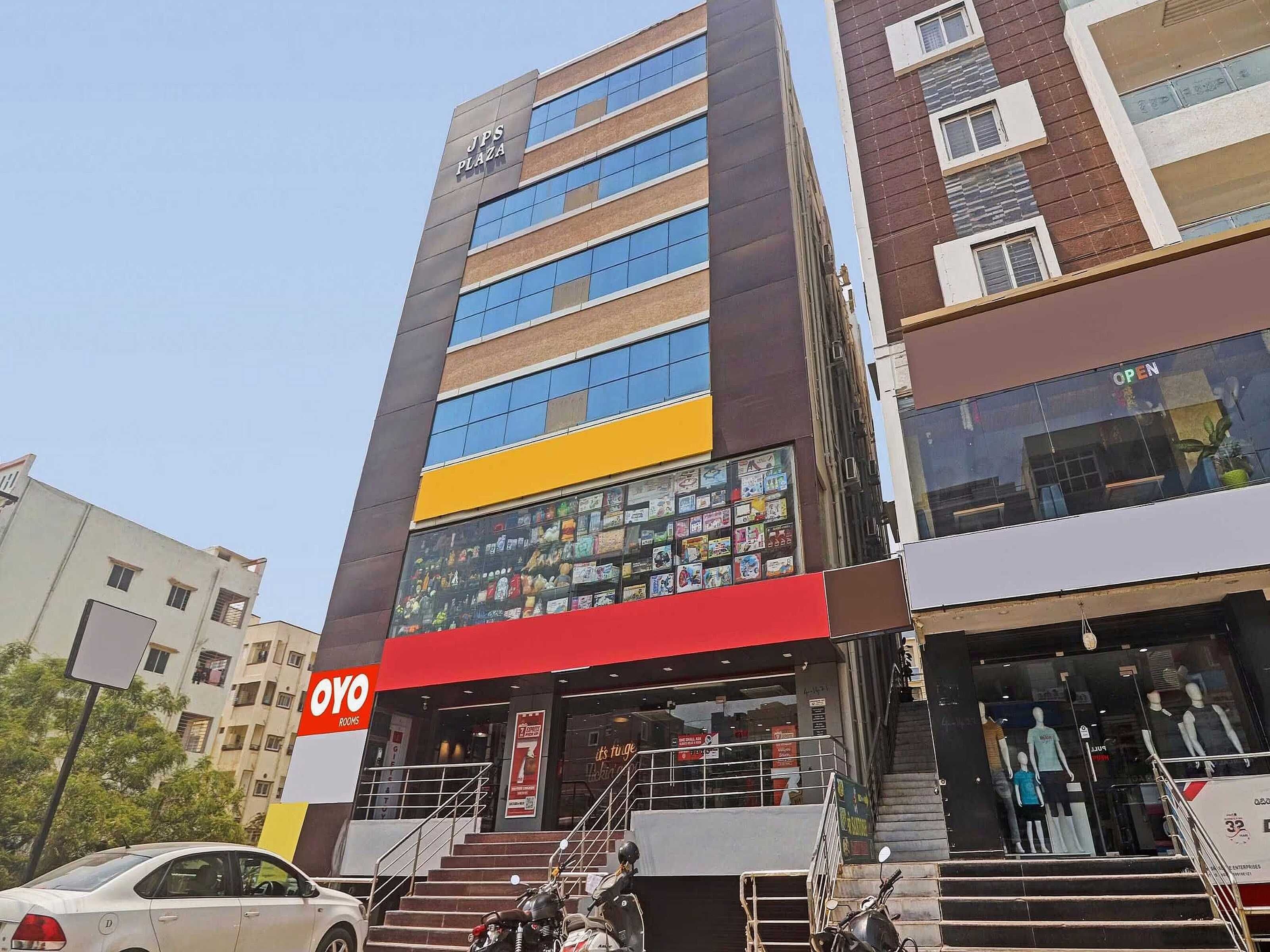 A multi-story building with a visible sign for 'JPS Plaza' and a storefront for 'Oyo Rooms' with a staircase leading to the entrance.