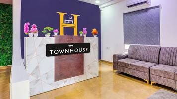 Ein Empfangsschalter mit einem 'TOWNHOUSE' Schild, ein Deckenventilator, eine Klimaanlage und ein graues Sofa.