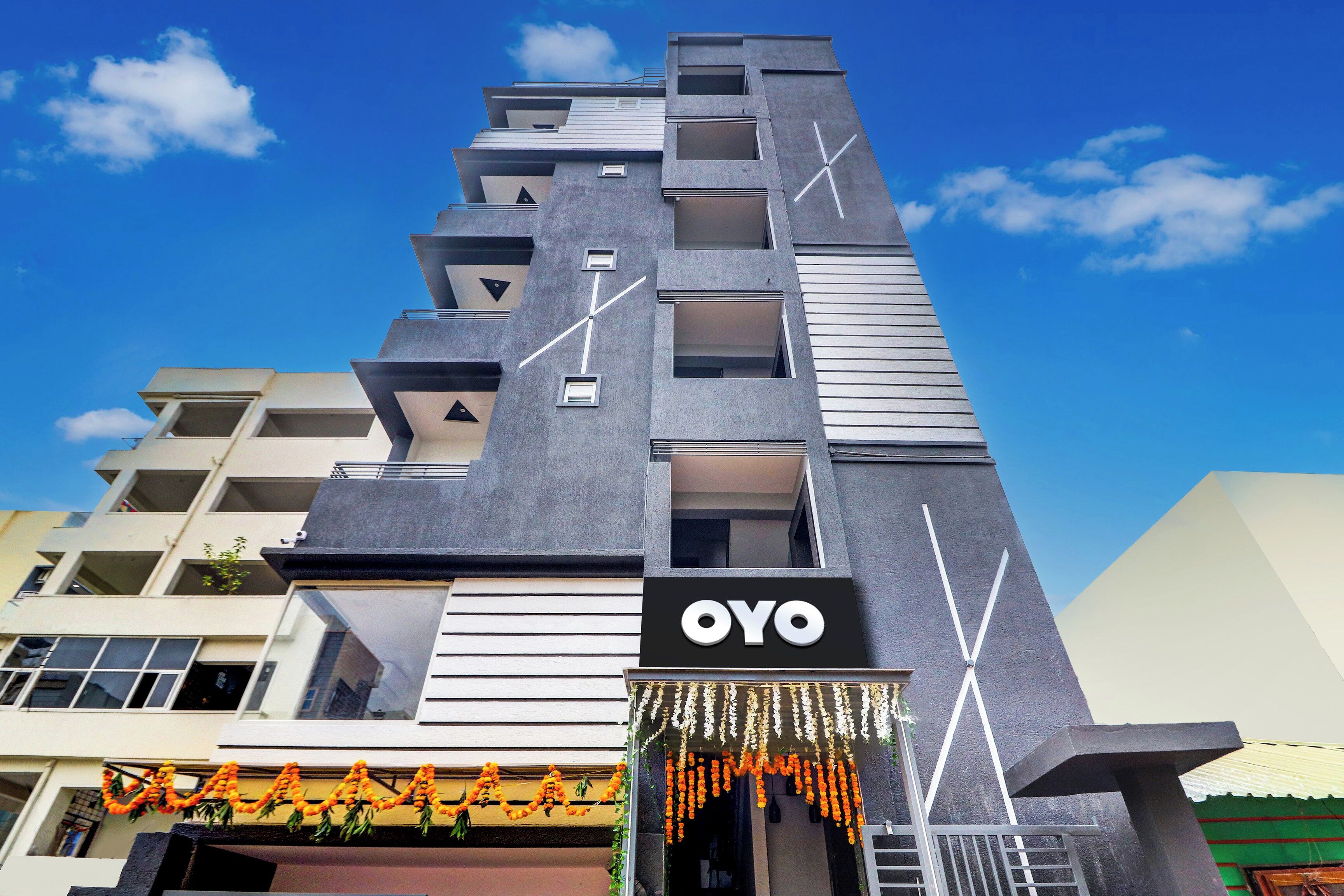 Ein modernes Gebäude mit einem auffälligen OYO-Logo, mehreren Balkonen und einer Reihe von Fenstern.