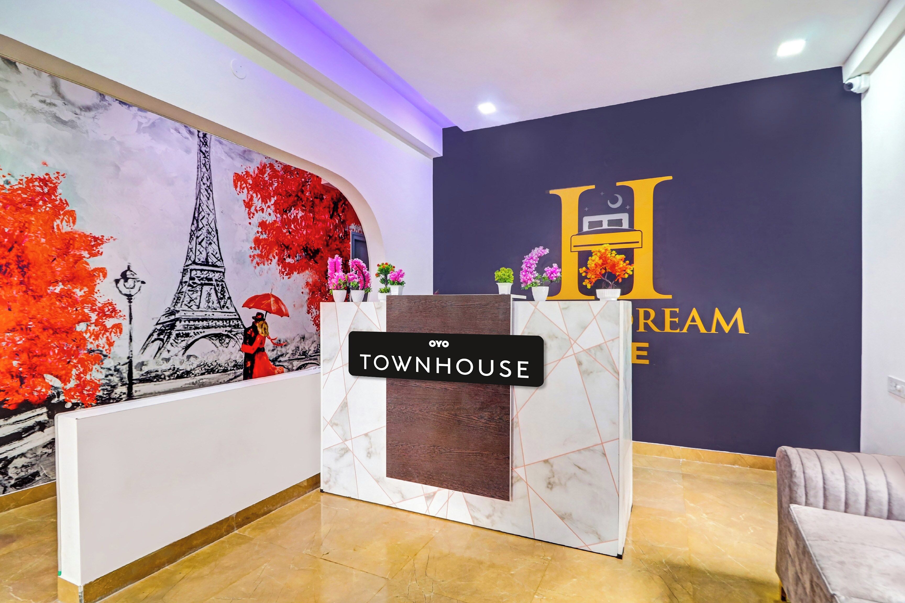 Una recepción con un letrero que dice 'TOWNHOUSE', un mural de la Torre Eiffel y un letrero en la pared que dice 'Dream House'.