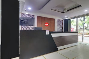 A reception area with a modern design, including a reception desk, a ceiling fan, and a sign with the logo 'OYO'. - HOTEL O SHAZEB INTERNATIONAL (Hyderabad)