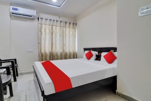 A hotel room with a bed, a desk, and an air conditioning unit. - Hotel O Shri Ganesh Residency (Hyderabad)