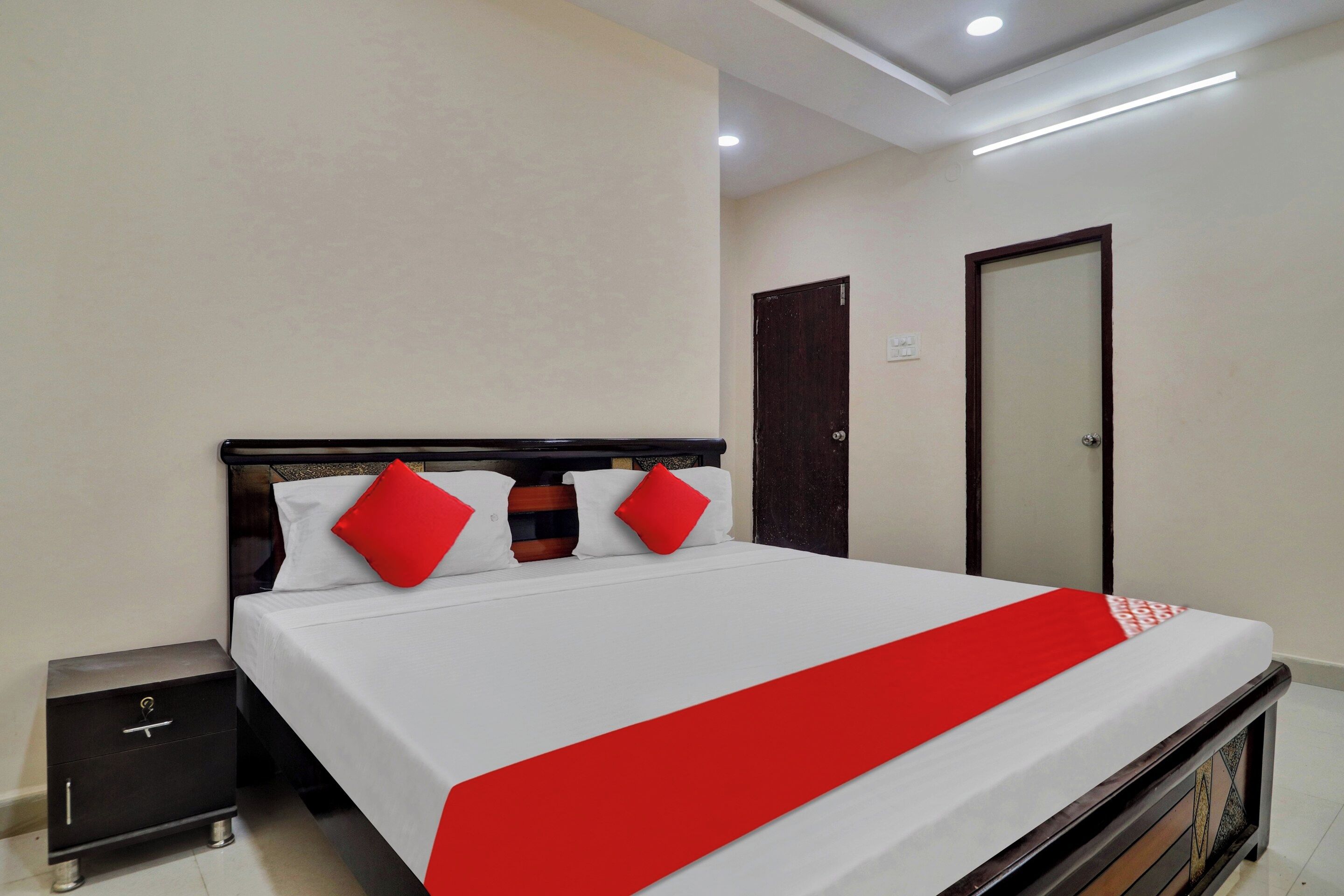 A hotel room with a bed, bedside tables, a wardrobe, and a door.