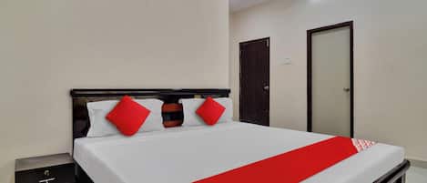 A hotel room with a bed, bedside tables, a wardrobe, and a door.