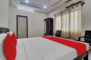 A hotel room with a bed, a wardrobe, a desk, and a chair. - Hotel O Shri Ganesh Residency (Hyderabad)
