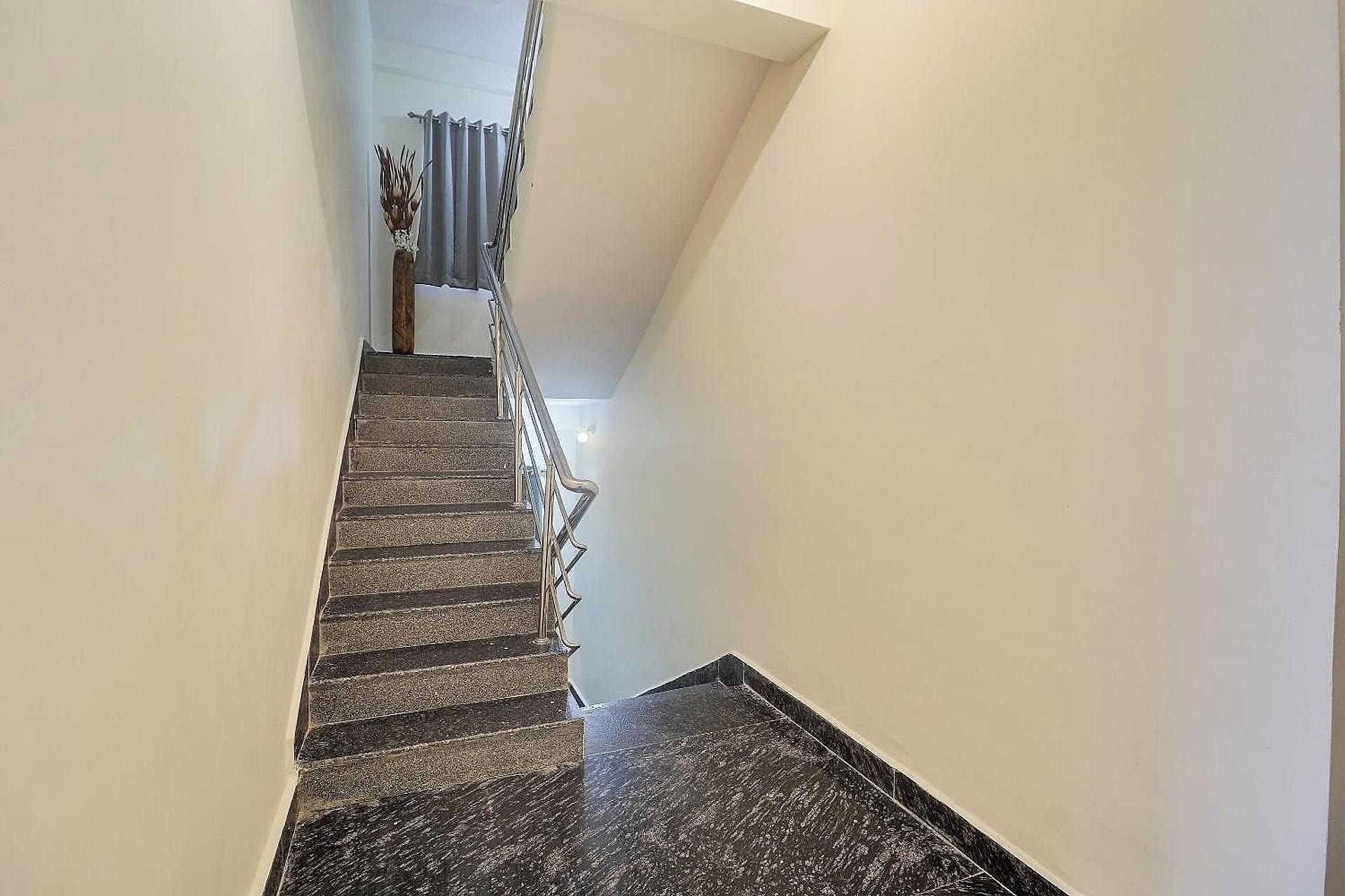 A staircase with a handrail, leading to a landing with a radiator and a curtain.