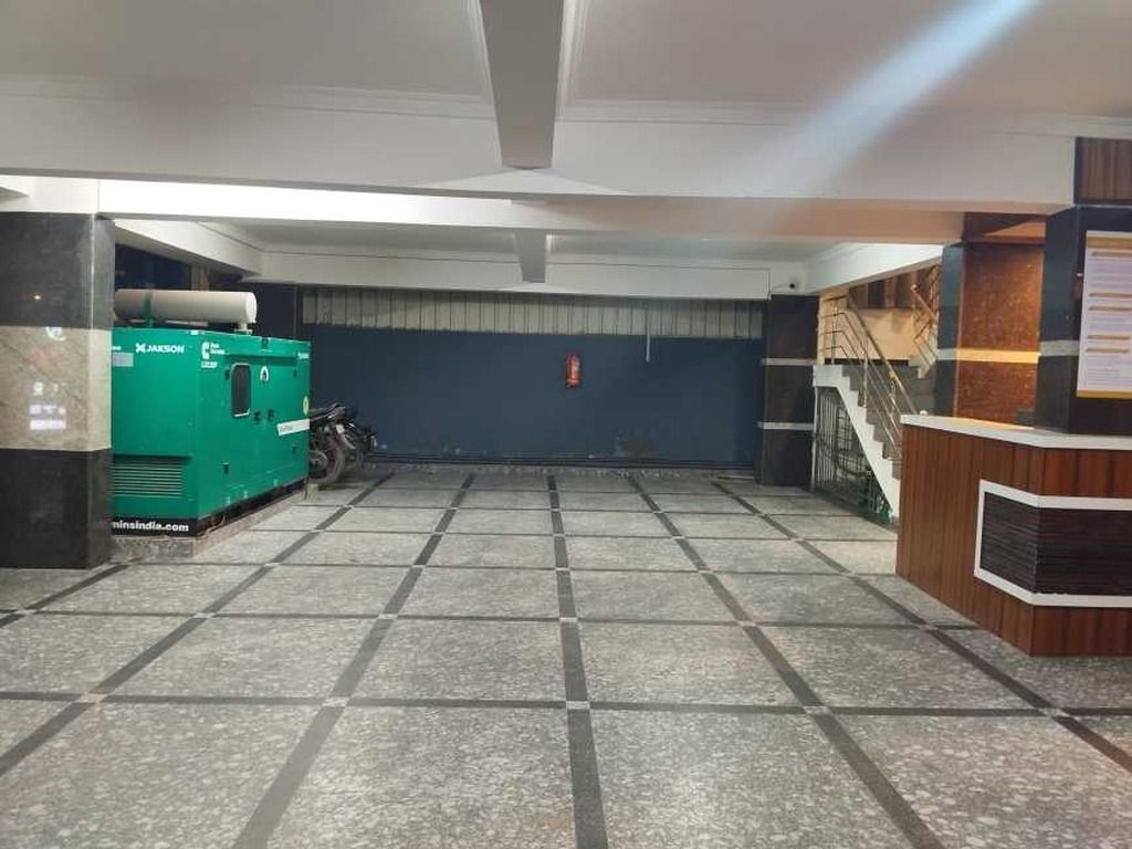A spacious lobby with a reception desk, a green machine, and a staircase.