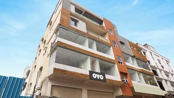 Un immeuble à plusieurs étages, avec une enseigne « OYO » bien visible au rez-de-chaussée, indiquant qu’il s’agit d’un hôtel ou d’une auberge de jeunesse.