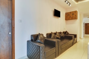 Un espacio moderno para sala de estar con un juego de sofá, un televisor de pantalla plana montado en la pared y un mueble de madera con detalles decorativos.