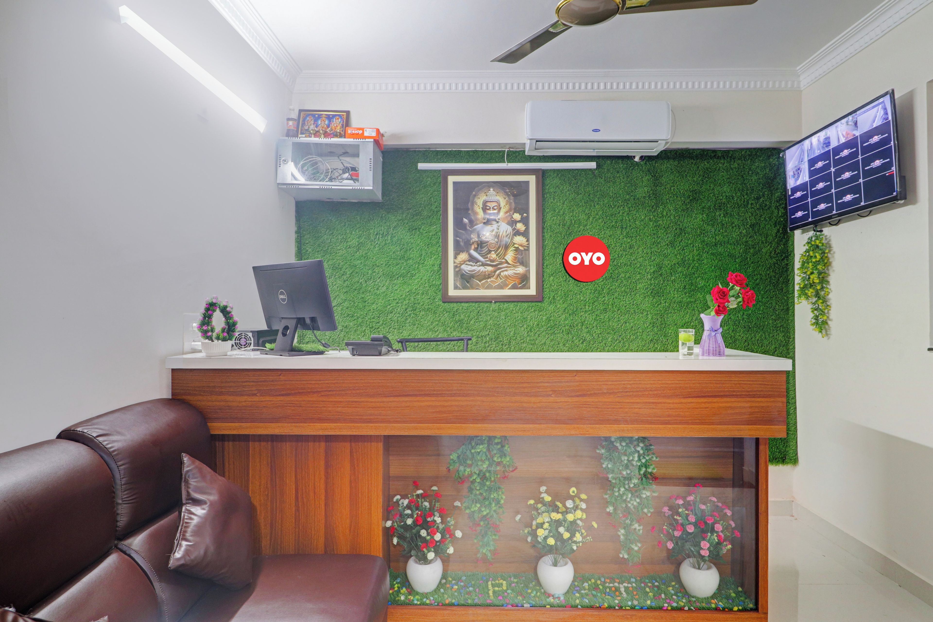 A reception area with a wooden desk, computer, and framed Buddha statue.