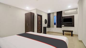 Habitación de hotel con cama, armario, mesita de noche, televisor y aire acondicionado.