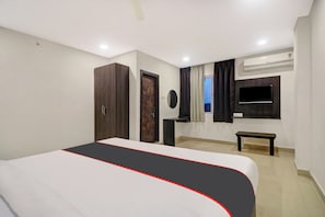 Ein Hotelzimmer mit Bett, Kleiderschrank, Nachttisch, Fernseher und Klimaanlage.