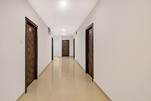 A corridor with doors on both sides, a tiled floor, and a ceiling with recessed lighting.