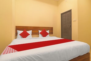 A bed with a white and red bedspread, two red pillows, and a wooden headboard. - Hotel O Ragas Inn (Hyderabad)
