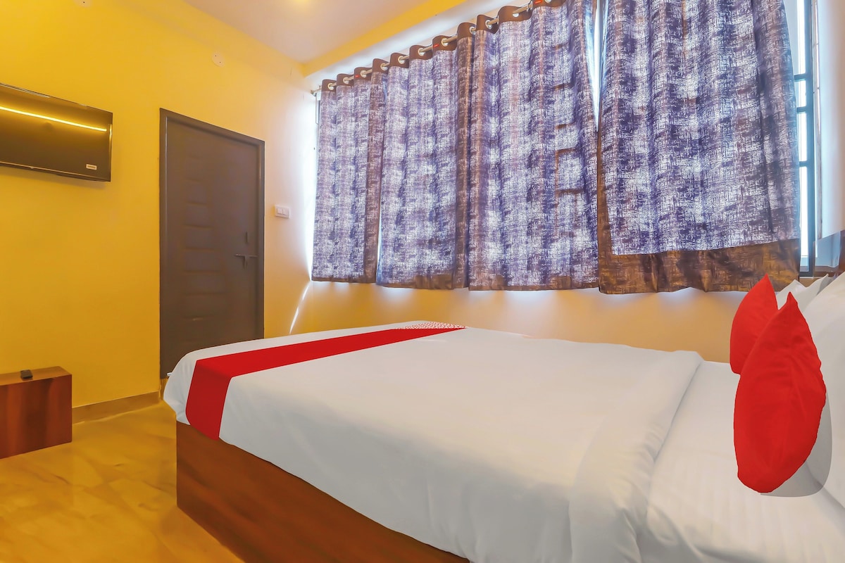 A hotel room with a bed, a door, and a window with curtains.