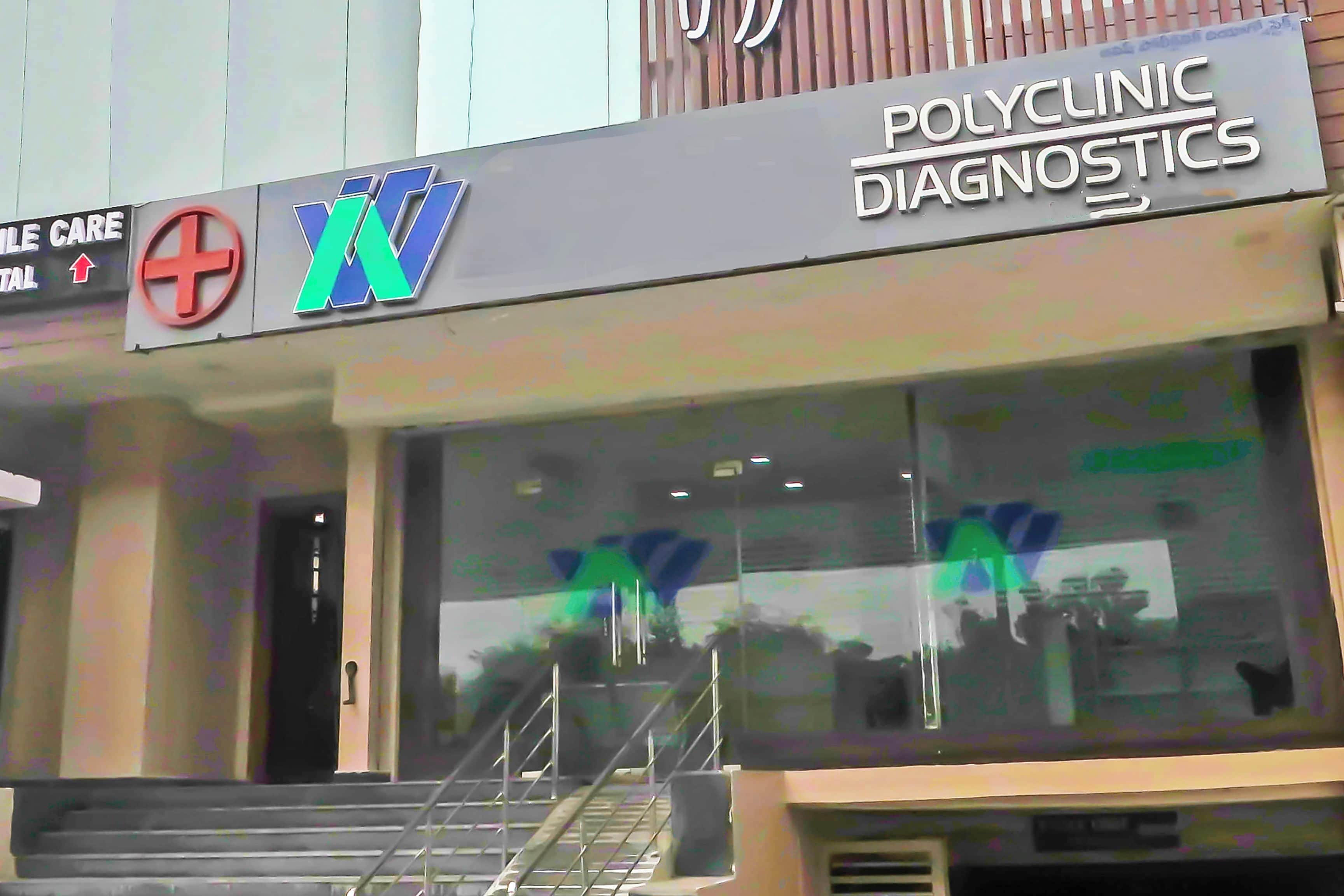 En bygning med et skilt for 'POLYCLINIC DIAGNOSTICS' og et logo med et plus-symbol og bogstavet 'M'.