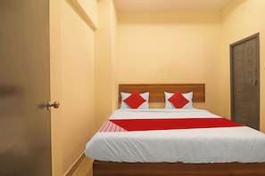 A hotel room with a single bed, a wooden headboard, and a red accent pillow. - Hotel O Ragas Inn (Hyderabad)