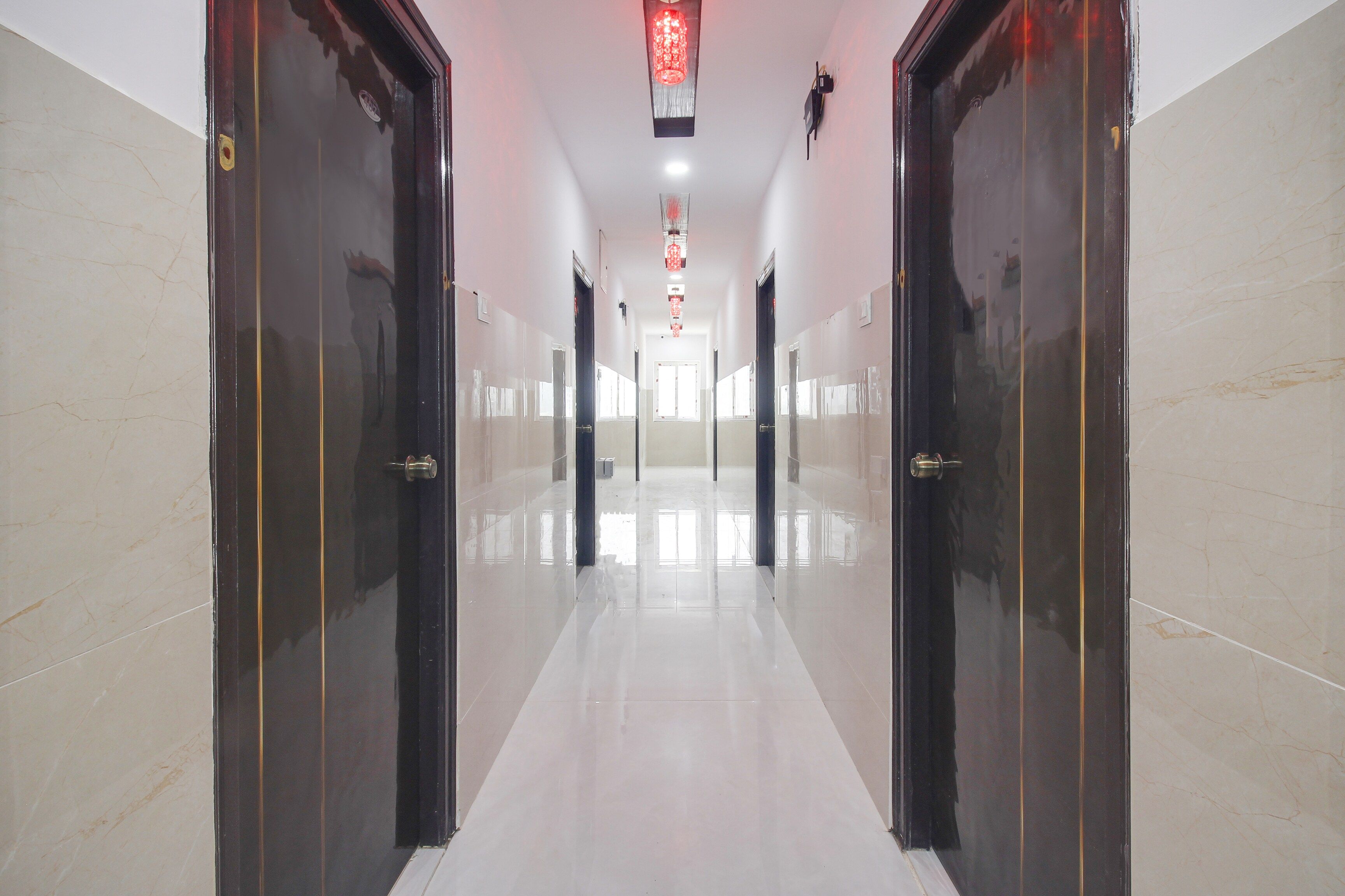 A corridor with two doors on either side, leading to a bright room with a large window.