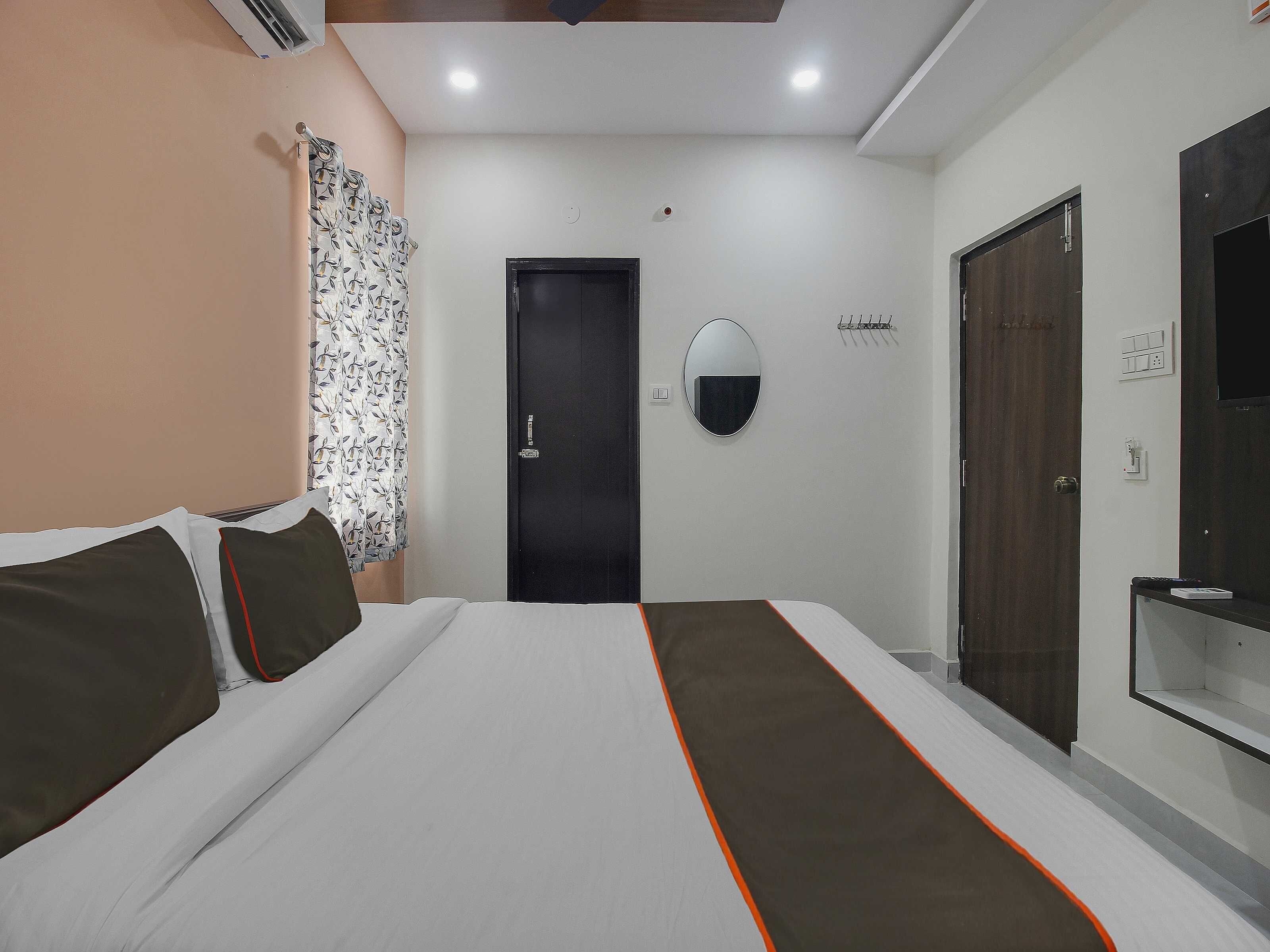 Une chambre d’hôtel avec un lit, une porte, un miroir et une armoire.