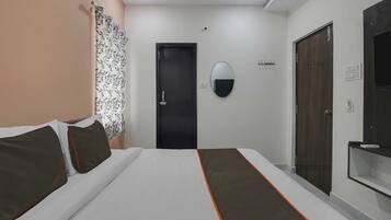Une chambre d’hôtel avec un lit, une porte, un miroir et une armoire.