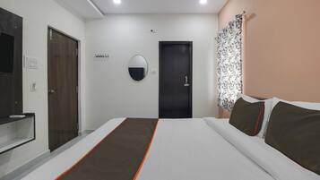 Une chambre d’hôtel avec un lit, un miroir, une porte et un luminaire fixé au mur.