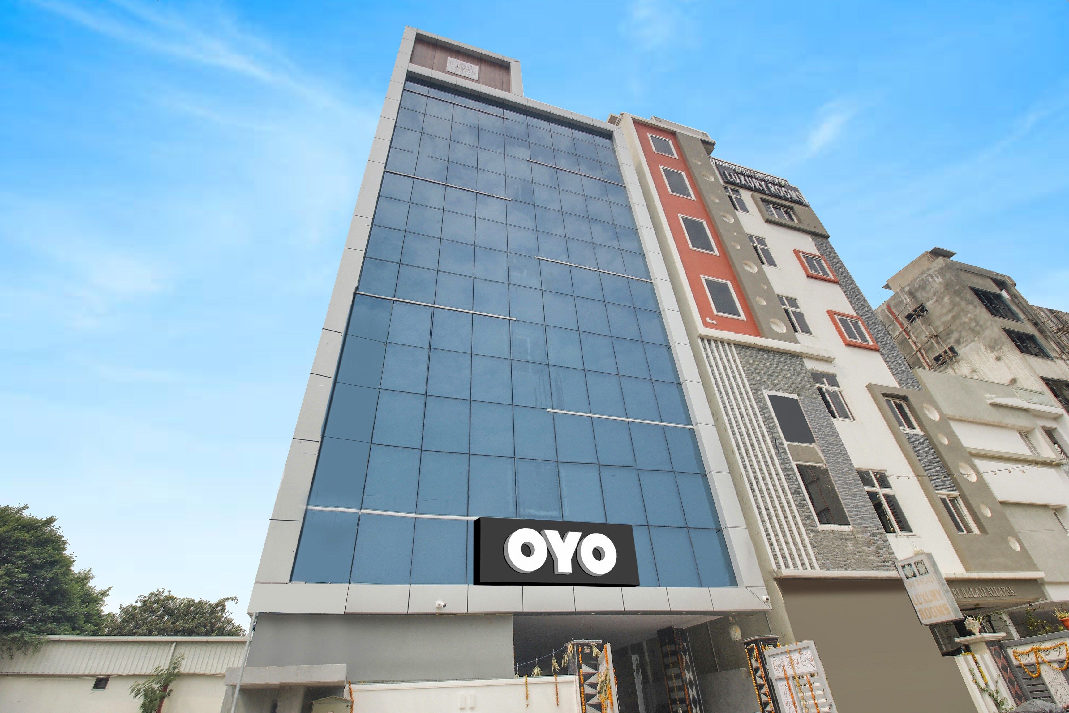 Un bâtiment moderne doté d’une façade en verre remarquable et d’une enseigne « OYO » placée en bas.