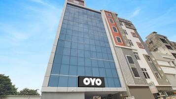 Un bâtiment moderne doté d’une façade en verre remarquable et d’une enseigne « OYO » placée en bas.