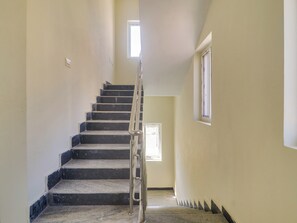 Una escalera con barandilla que lleva a un descansillo con ventana.