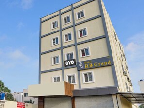 Un hotel de varios pisos con un cartel que indica 'Hotel RB Grand' y 'Habitaciones de lujo'.