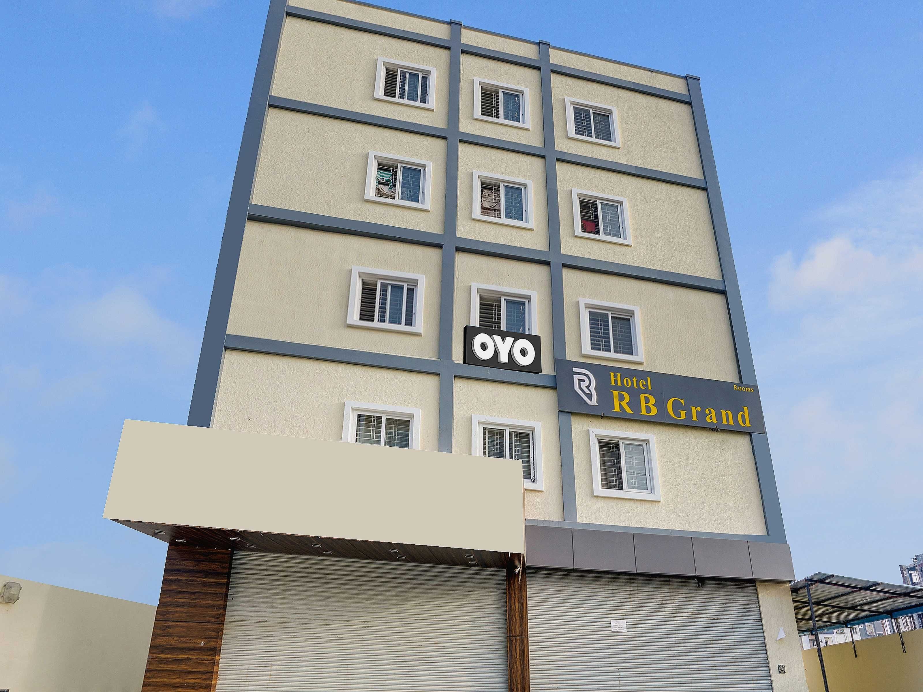 Un edificio de hotel de varios pisos con un letrero que dice 'Hotel RB Grand' y el logotipo de 'OYO'.
