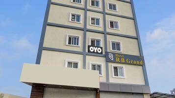 Un edificio de hotel de varios pisos con un letrero que dice 'Hotel RB Grand' y el logotipo de 'OYO'.