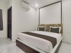 Ein Hotelzimmer mit Bett, einer Tür, einer Klimaanlage und einem wandmontierten Spiegel.