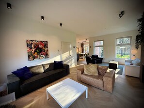 A modern living room with a sofa, a coffee table, and a painting on the wall. - New Listing (Zeewolde)