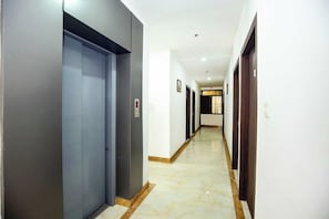 Un pasillo con puertas a ambos lados, piso de baldosas e iluminación empotrada en el techo.
